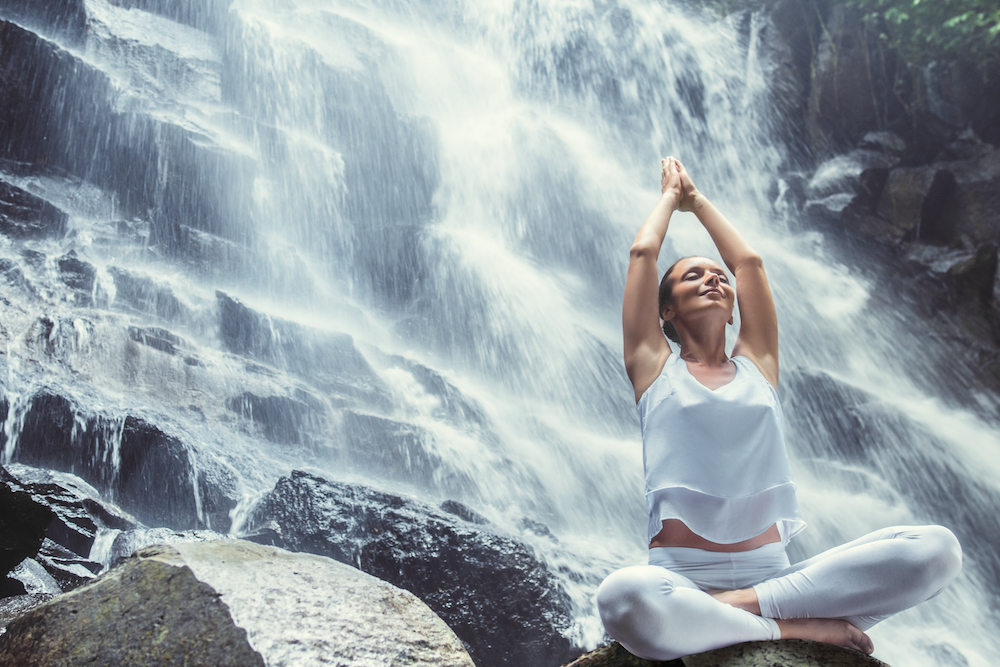 Woman doing yoga in front of a waterfall after IV hydration therapy in Minneapolils
